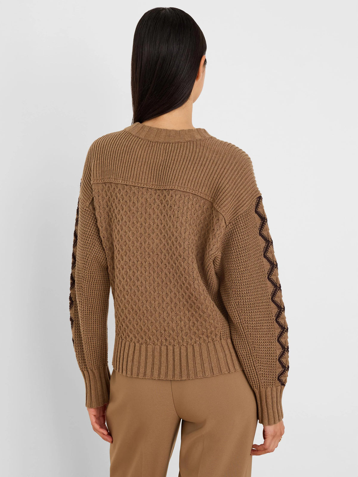 Camel brown sweater features ribbed edges, a textured diamond knit body, and dark zig-zag patterns on the sleeves.