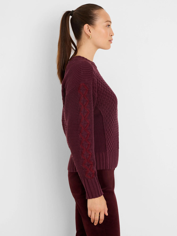 Burgundy knit sweater with criss-cross pattern on sleeves and cable knit body.