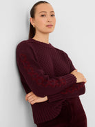 Maroon textured knit sweater with a criss-cross zigzag pattern on the sleeves. Features ribbed cuffs, hem, and neckline.