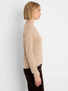 Beige long-sleeve sweater with shimmering beadwork on the right shoulder.