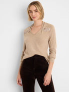Light beige V-neck sweater with shimmering, cinched embellishments at the shoulders.