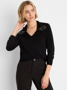 Black V-neck sweater with metallic beaded embellishments on each shoulder, framing the neckline.