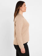 Tan long-sleeve sweater with sparkling embellishment on the shoulder.