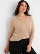 Beige V-neck sweater with beaded, cinched shoulder details.