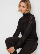 Black knit lace turtleneck sweater with diamond openwork pattern on sleeves and upper body.