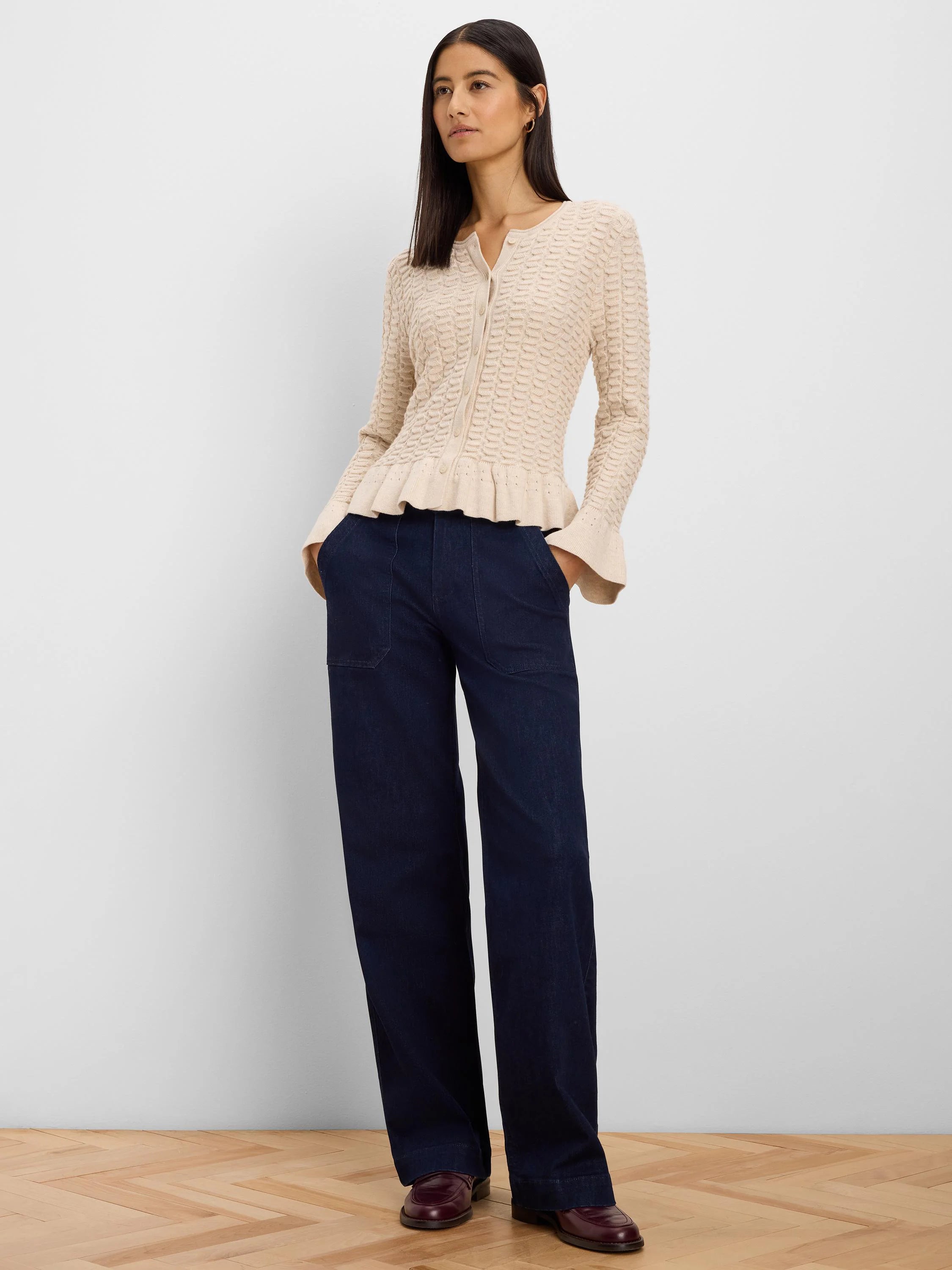 Cream button-front cardigan with a wavy textured knit pattern and a gathered, frilled hem.