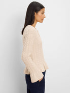 Pale beige cardigan with raised knit texture, frilled hem & cuffs, and front buttons.