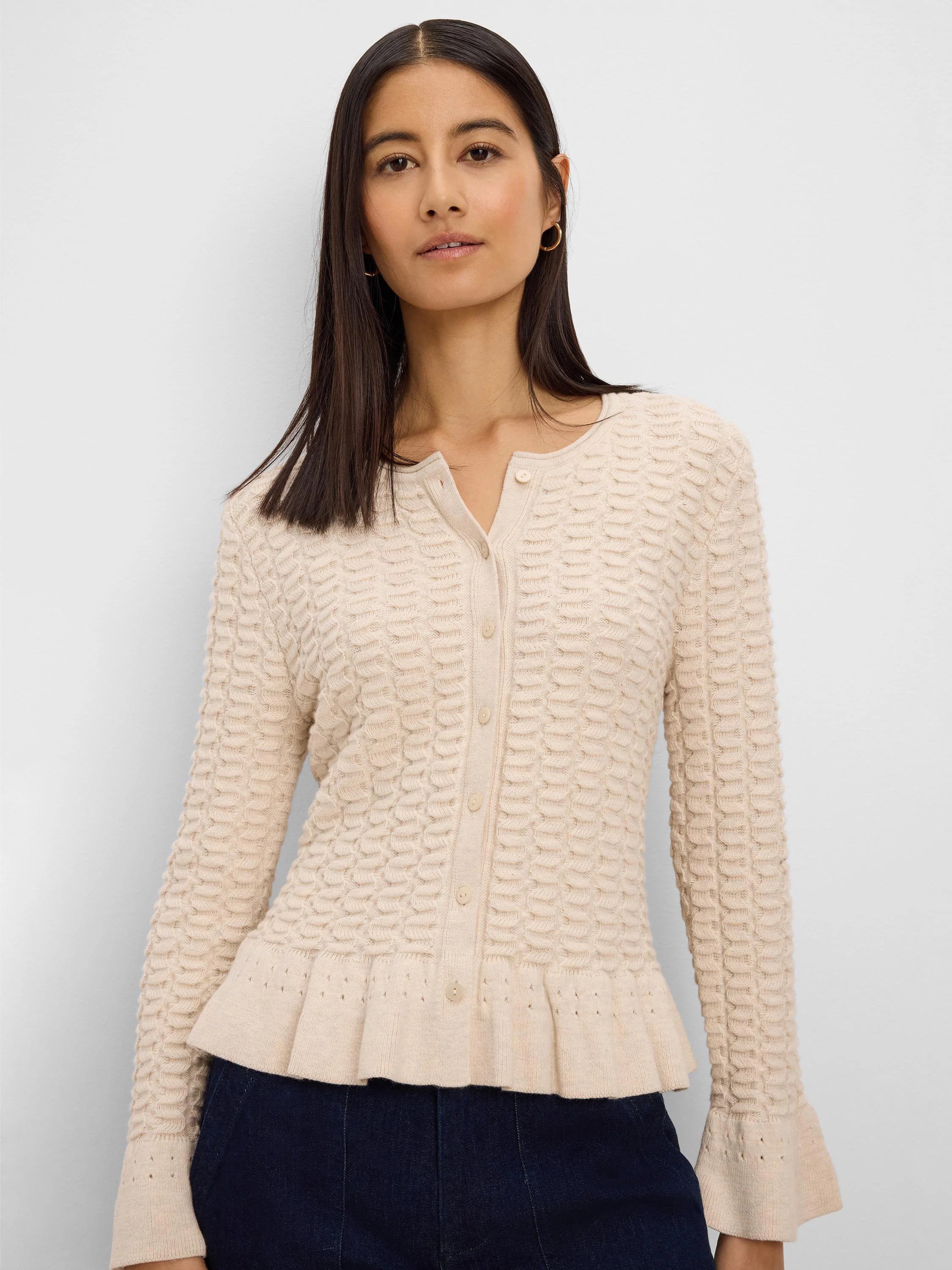 Cream textured knit cardigan with button front, V-neck, ruffled peplum hem, and flared cuffs.