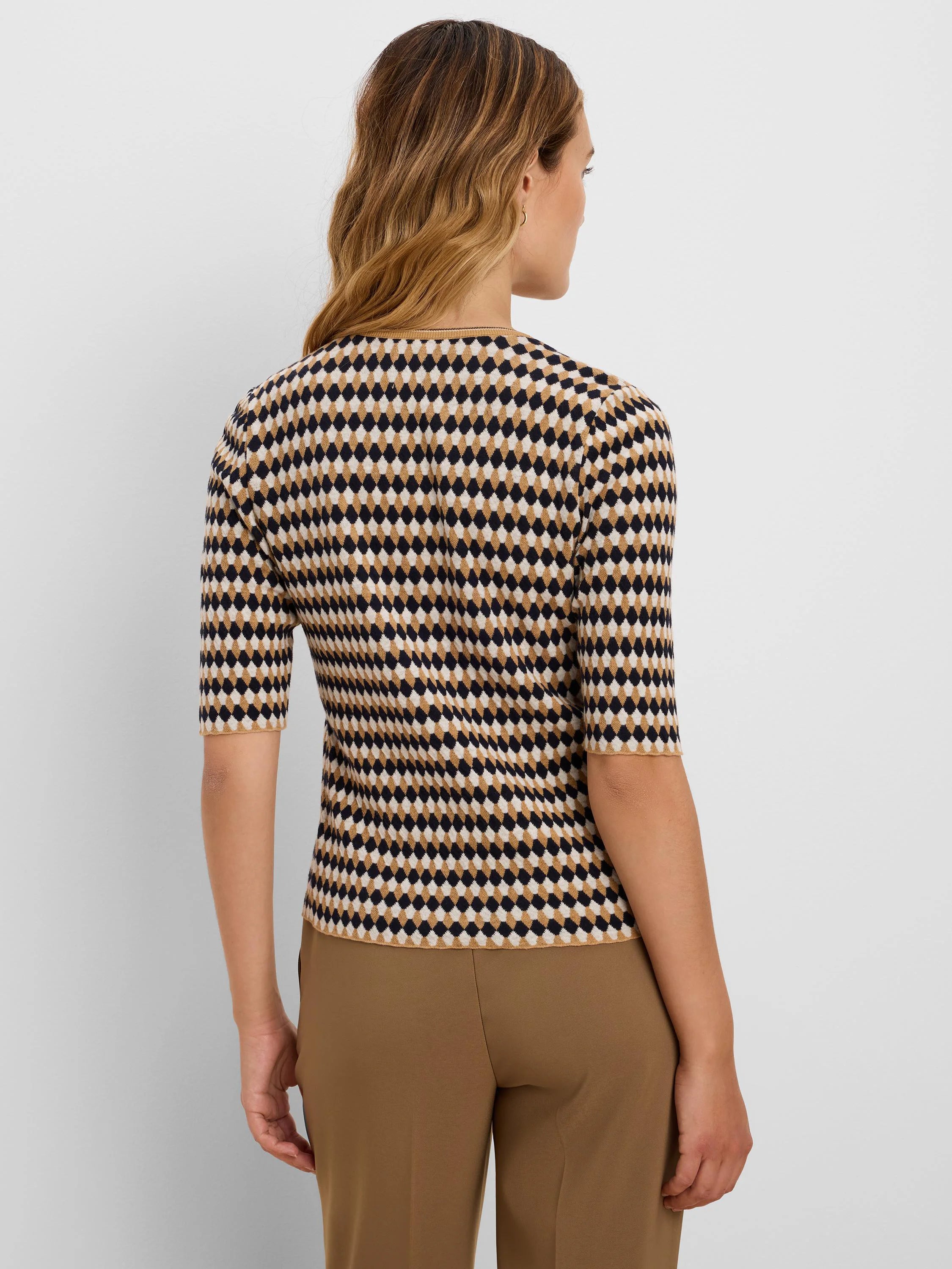 Angled jacquard sweater with dark navy, cream, and camel diamond pattern and elbow sleeves.