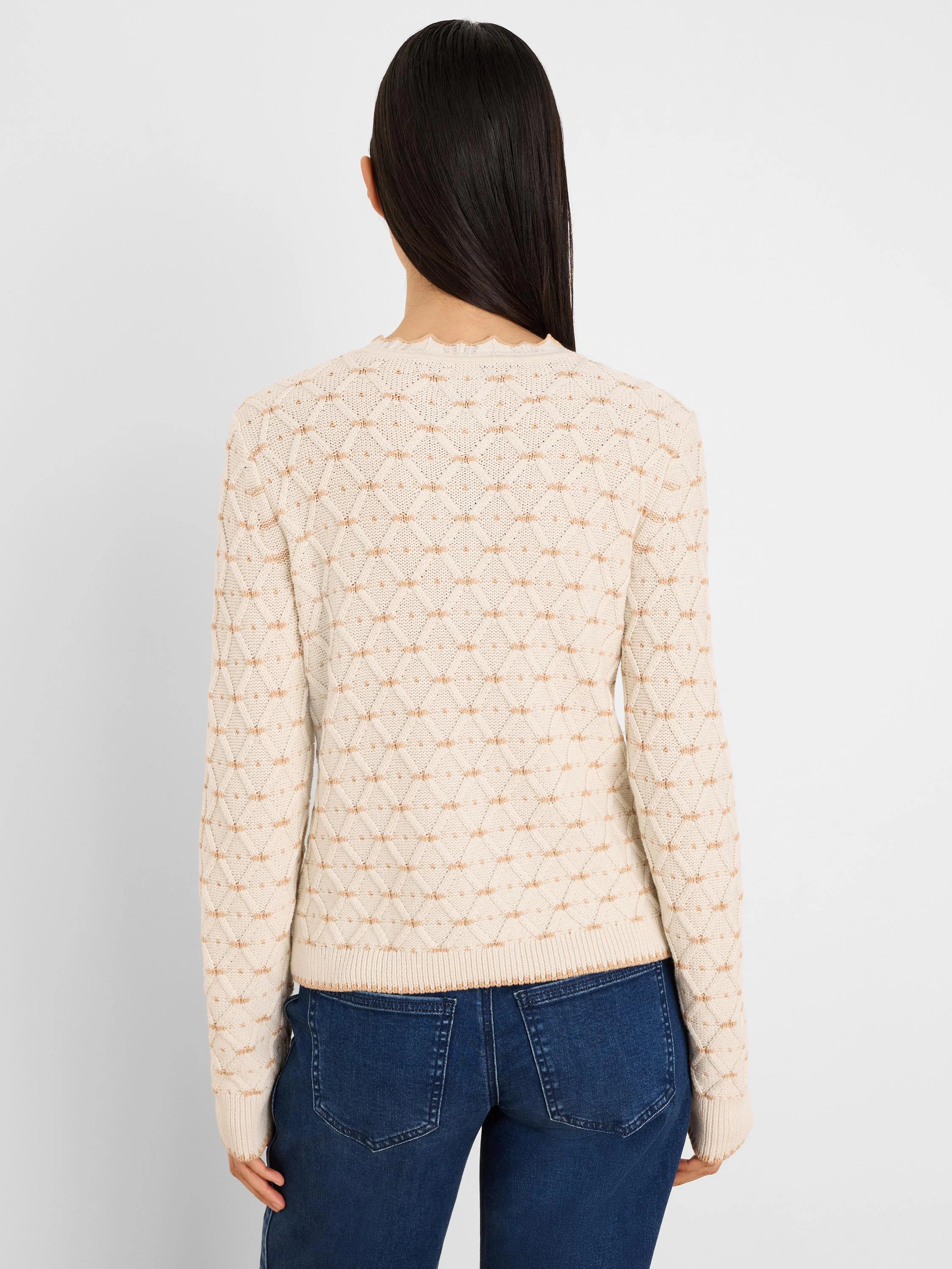 Cream sweater with tan diamond knit pattern, ruffled neckline, and ribbed cuffs. Back view.