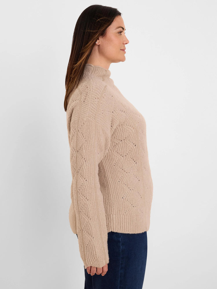Beige mock neck sweater featuring a diamond knit pattern, worn by model.