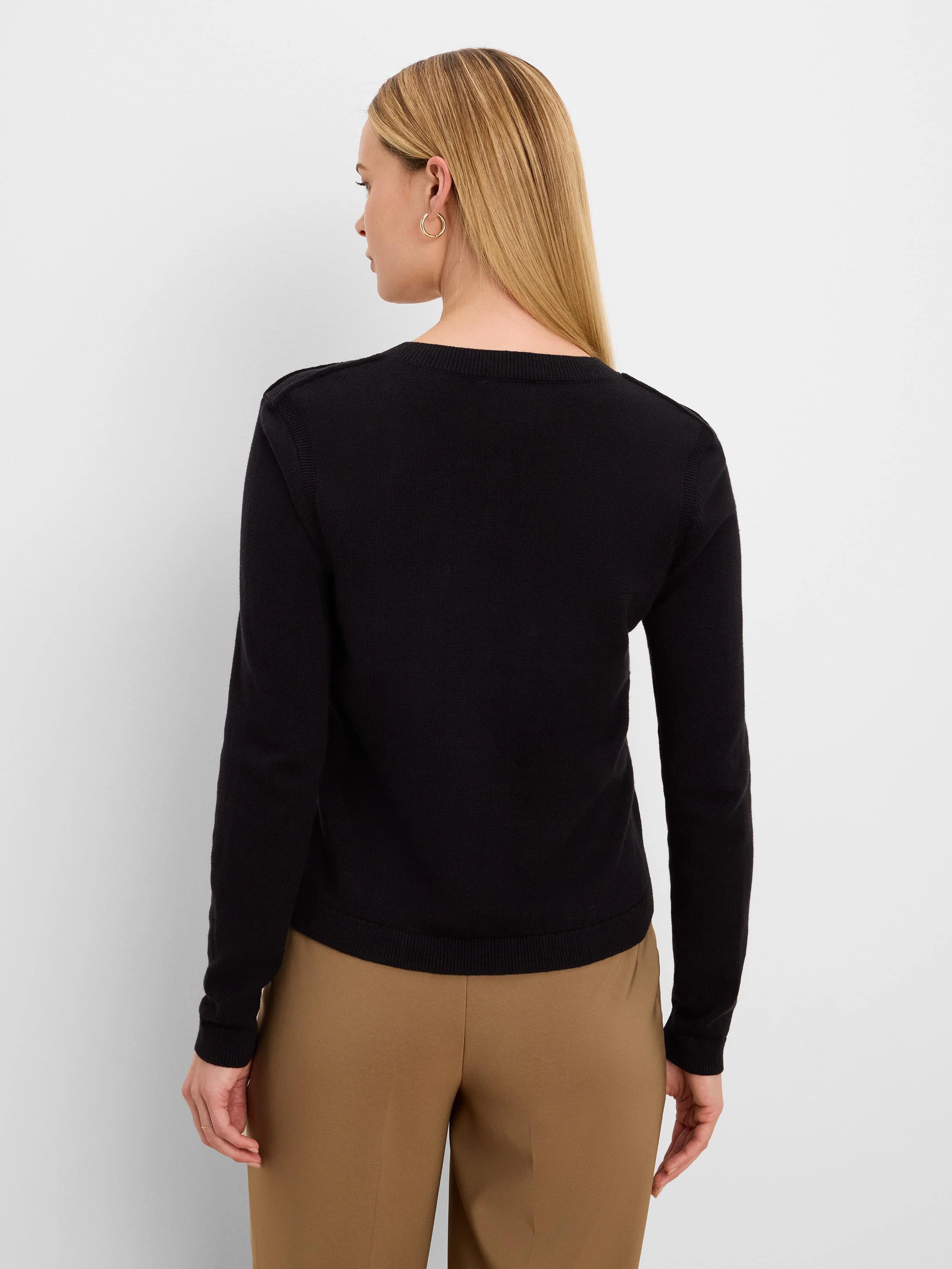 Black long-sleeve knit cardigan on model, viewed from back. Ribbed neckline, cuffs, and hem.