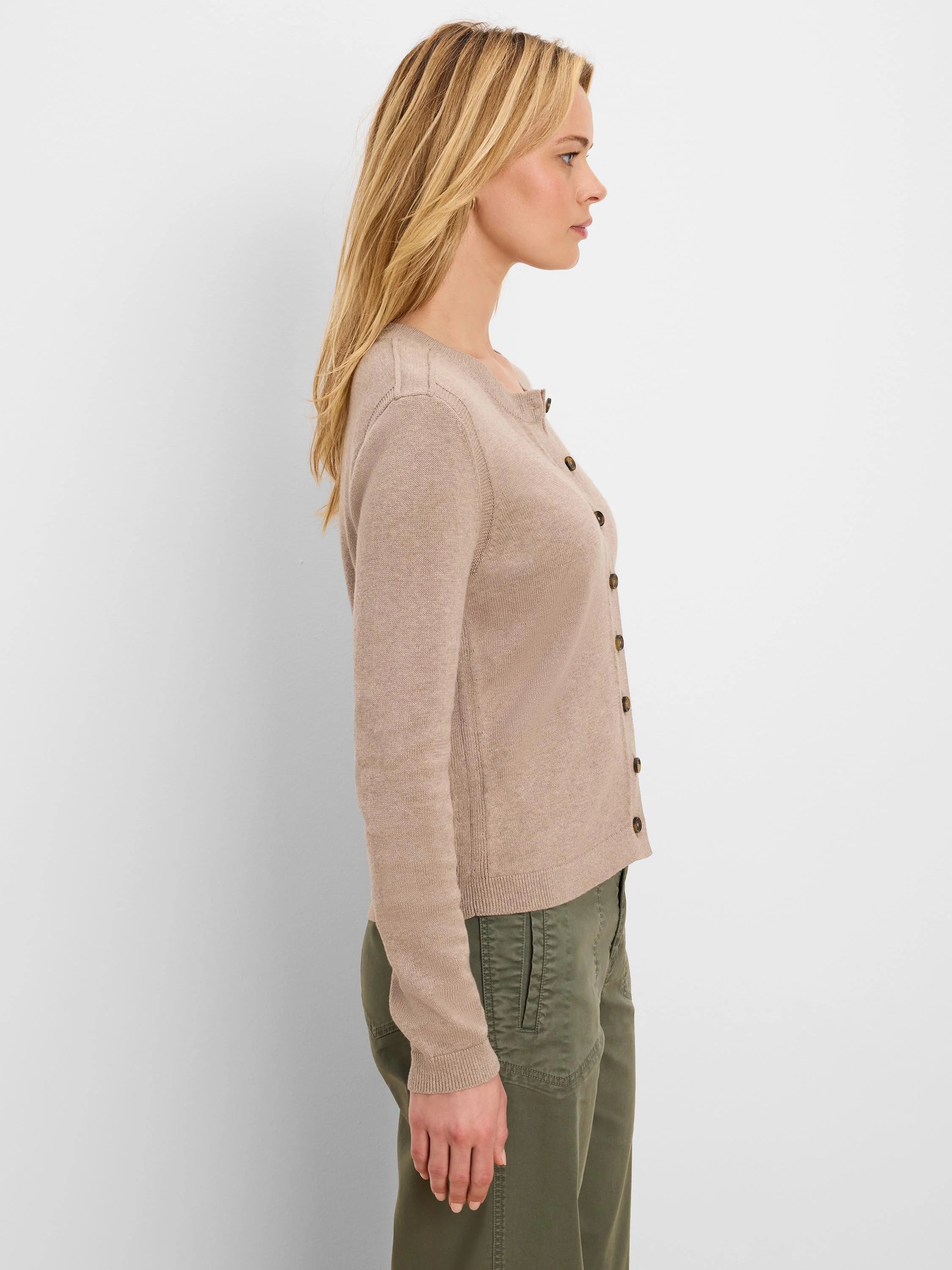 Light beige pure cotton cardigan on model. Features round neck, dark brown buttons, long ribbed sleeves and hem.