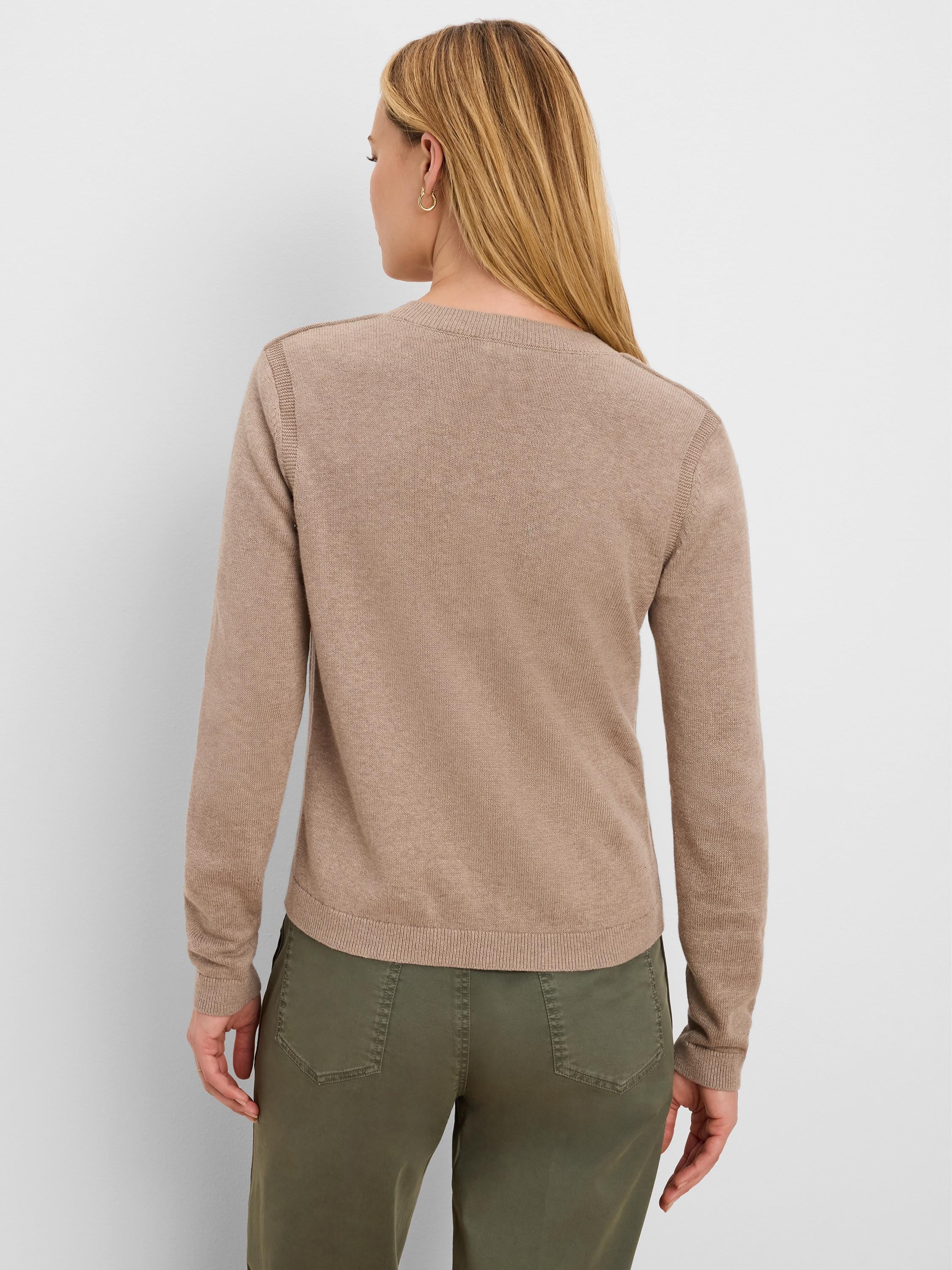 Back of a woman in a beige fine-knit cardigan. Features long sleeves, a ribbed hem, and neckline.