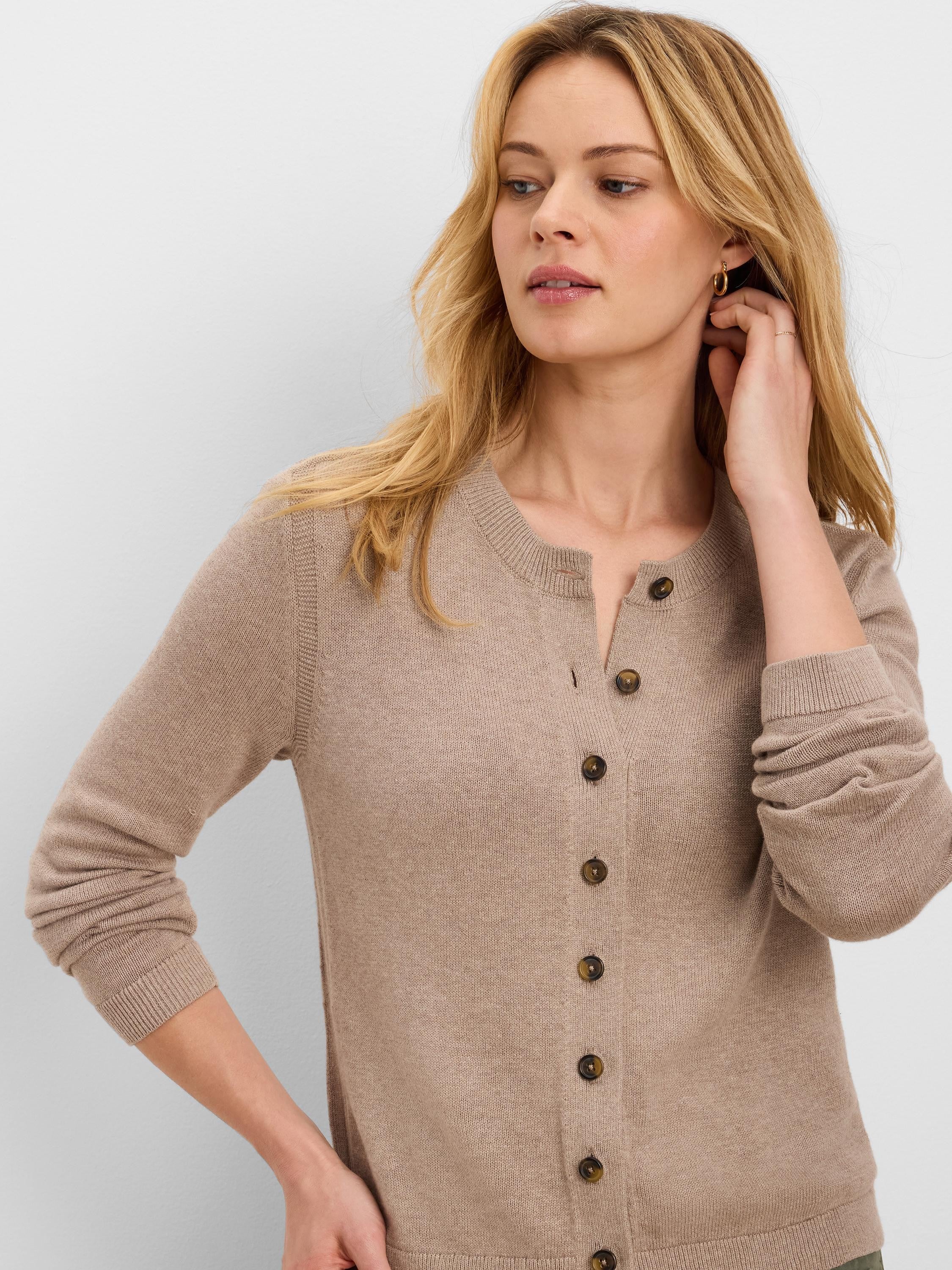 Light brown, round-neck cardigan featuring six visible dark brown speckled buttons. Worn by a woman.