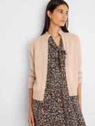 Pale pink knit open-front cardigan with ribbed collar, cuffs, and hem. Cropped.