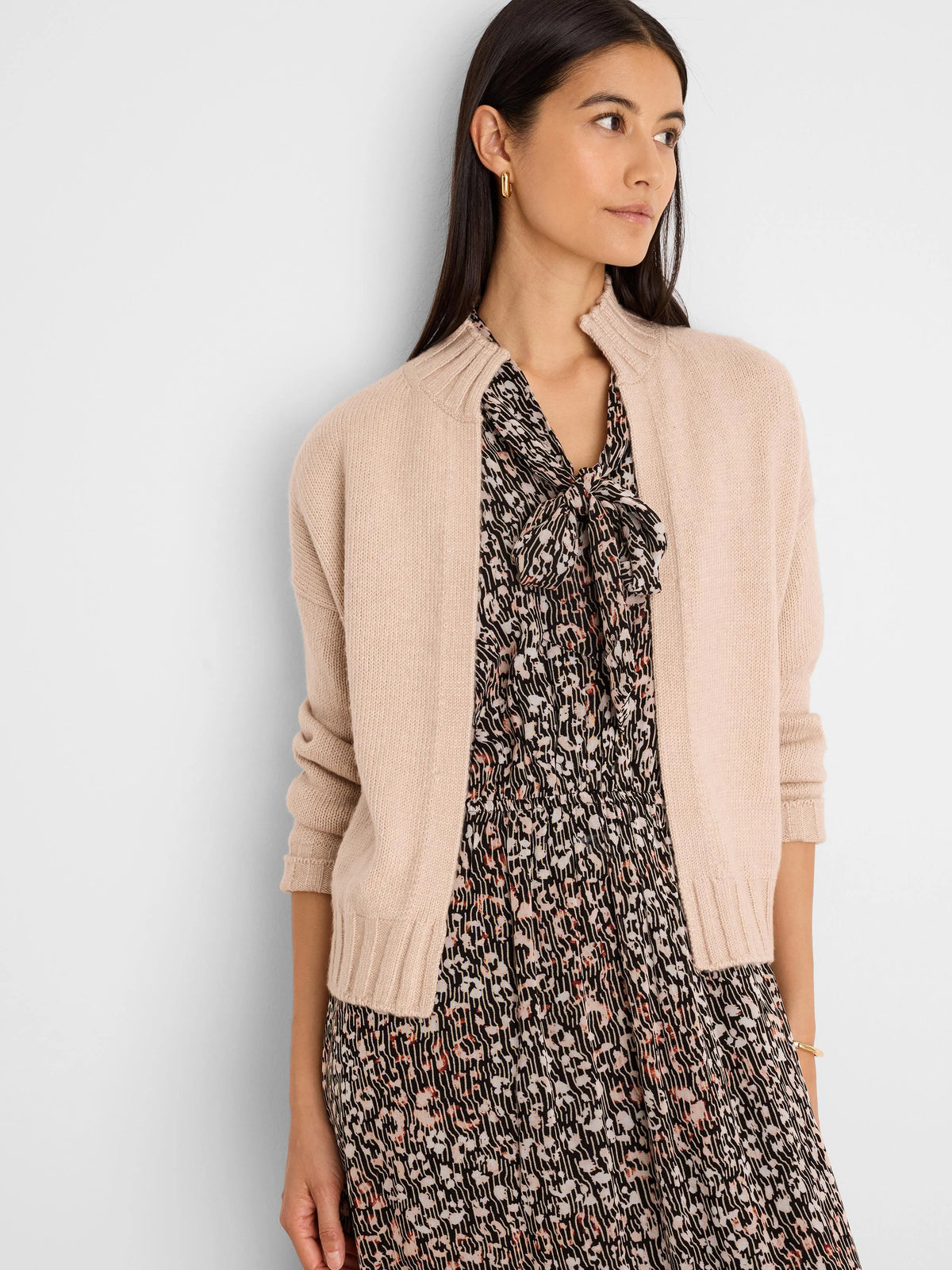 Pale pink knit open-front cardigan with ribbed collar, cuffs, and hem. Cropped.