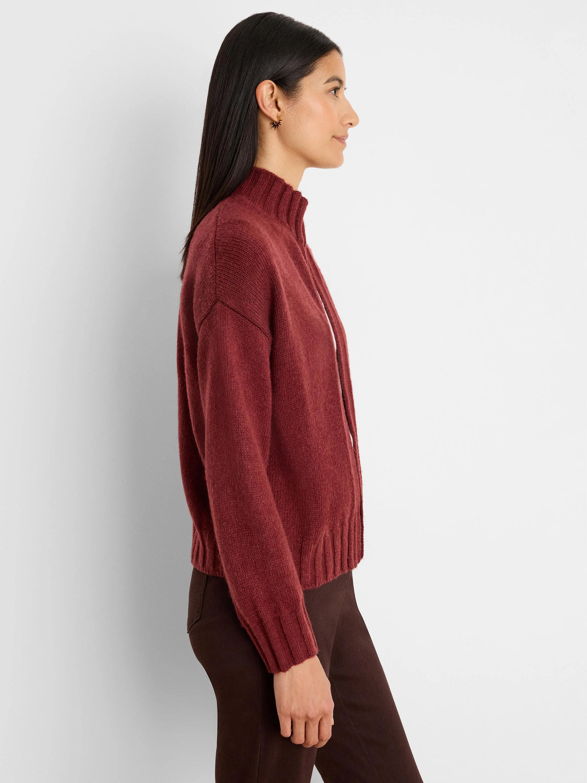 Burgundy knit cardigan with a mock neck, full zip closure, ribbed cuffs & hem. Model in profile.
