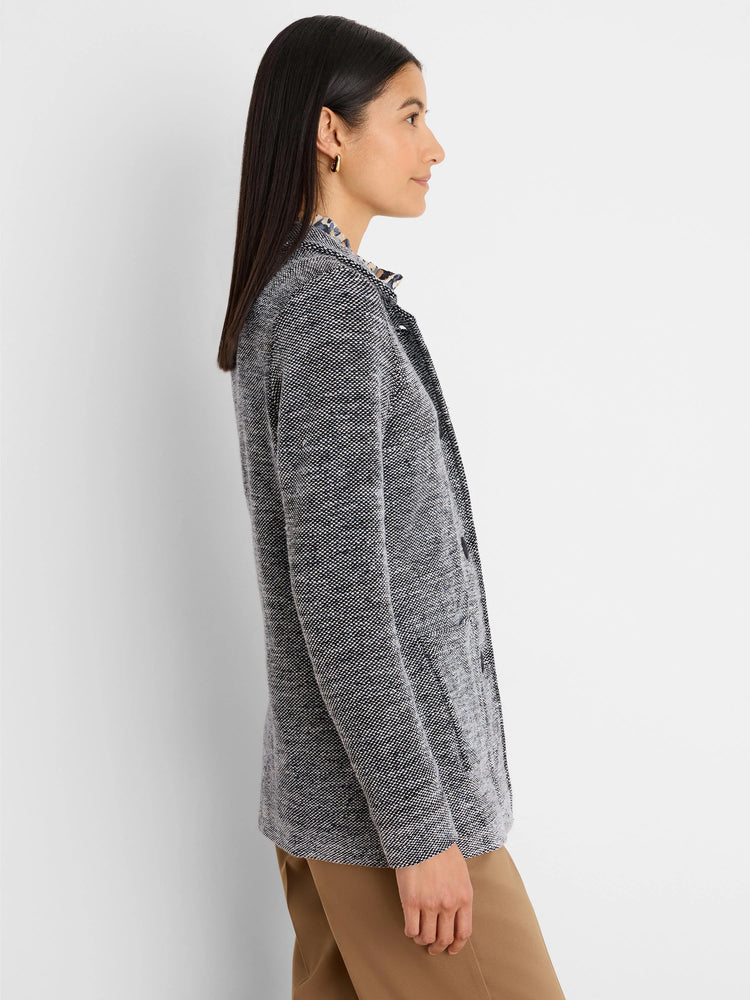 Model wears a black and white speckled tweed blazer-style sweater jacket, side view.