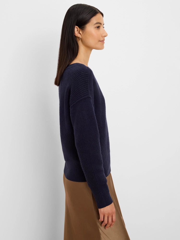 Navy blue ribbed knit sweater with long sleeves, worn by a model.