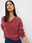 Rust-colored V-neck sweater with ribbed texture, relaxed fit, and long sleeves.