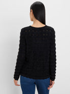 Black fuzzy sweater with a round neck, small perforated details on the back and sleeves, and a scalloped hem.