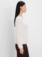 Off-white fuzzy sweater with a wavy openwork knit pattern.