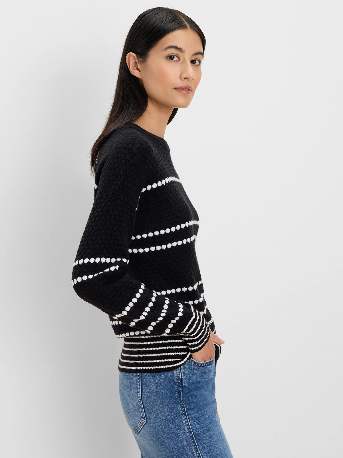 Black textured sweater with white horizontal dotted stripes; ribbed black/white cuffs and hem.