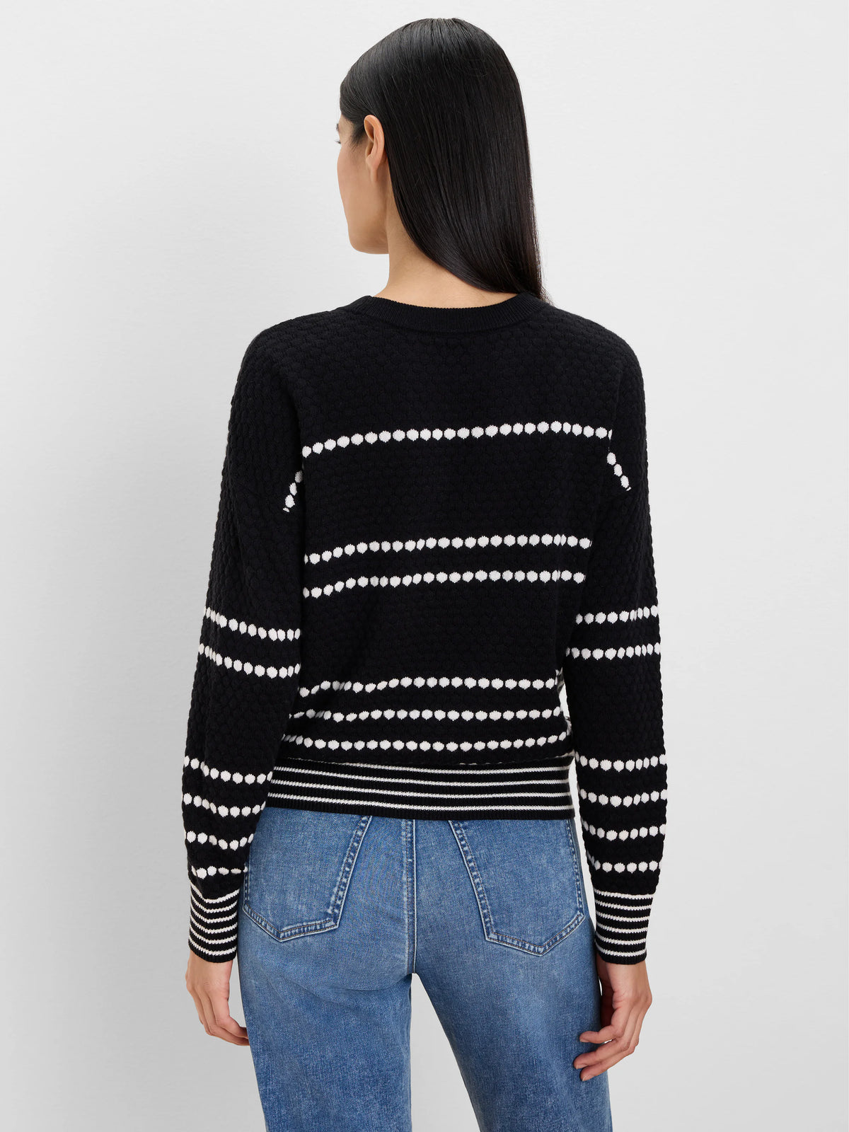 Black sweater with horizontal rows of white textured dots. White stripes on ribbed cuffs and hem.
