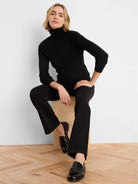 Black, vertically ribbed knit turtleneck worn by a model.