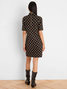 Black and tan geometric knit dress, short sleeves, high neck, with a visible gold zipper down the back.