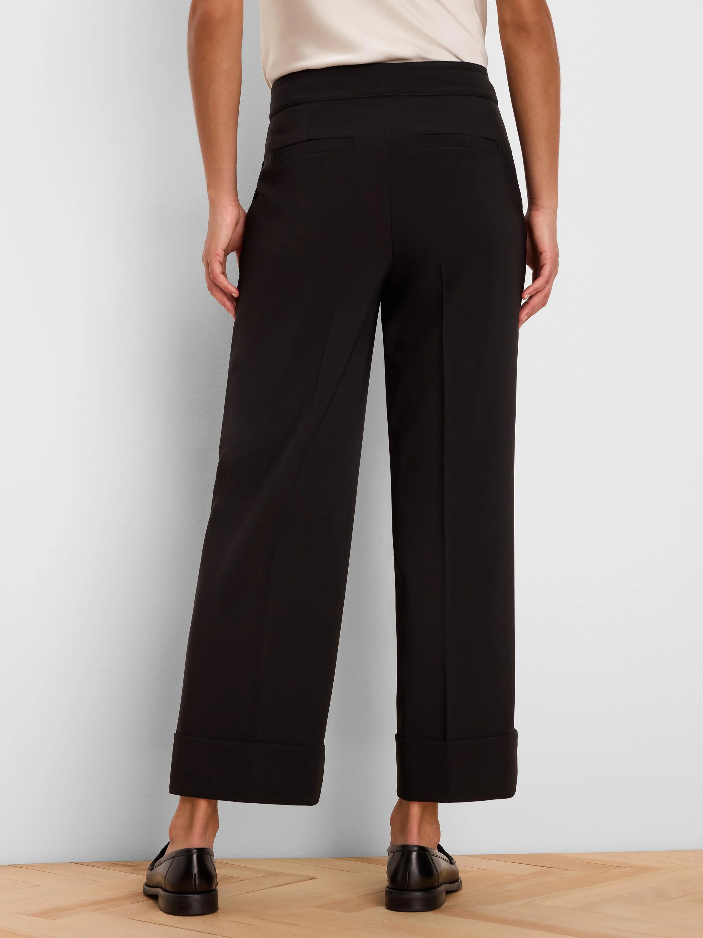 Black wide-leg ankle pants with cuffed hems and two back welt pockets, shown from the rear.