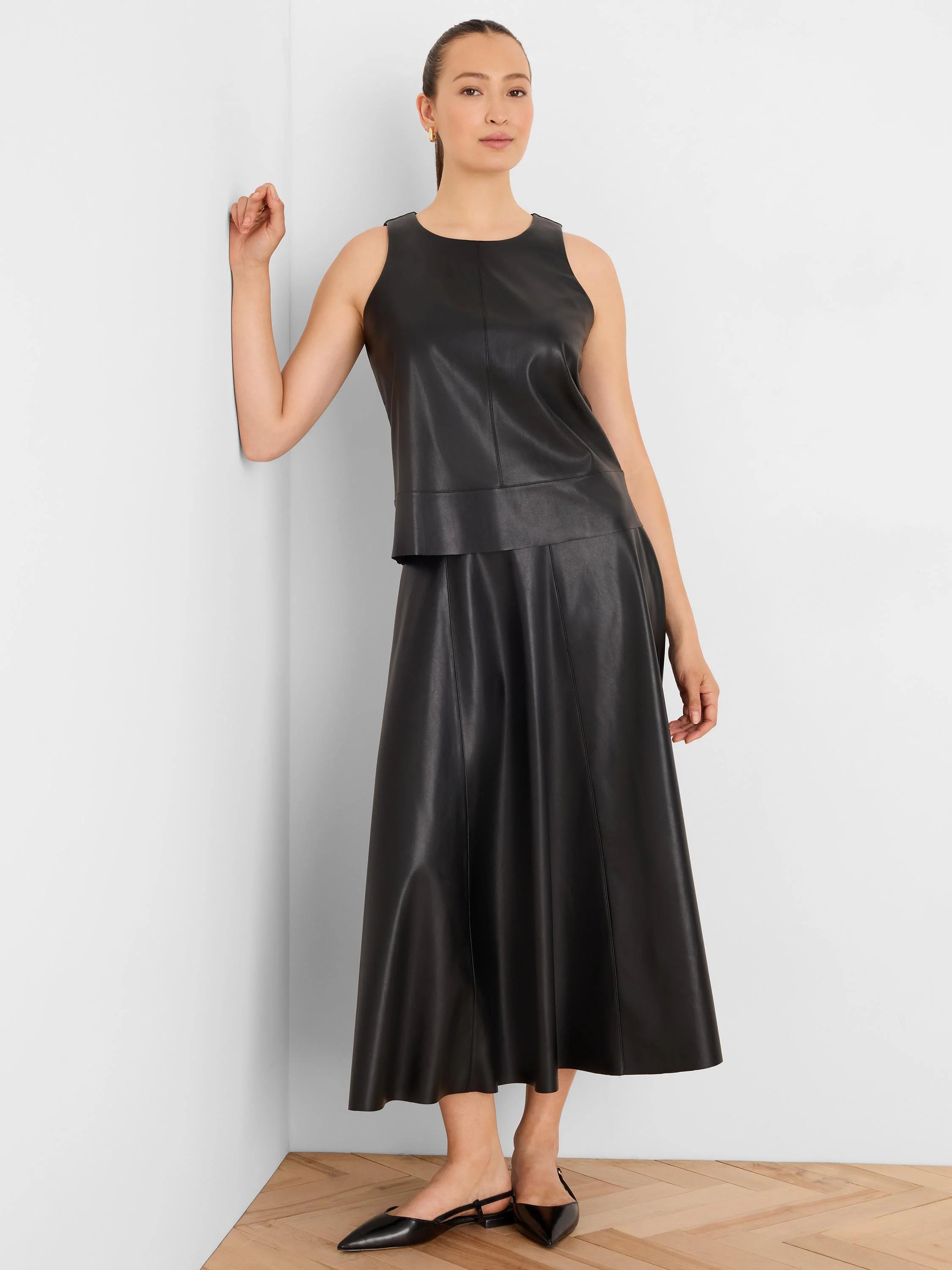Black vegan leather A-line midi skirt with visible vertical seams.