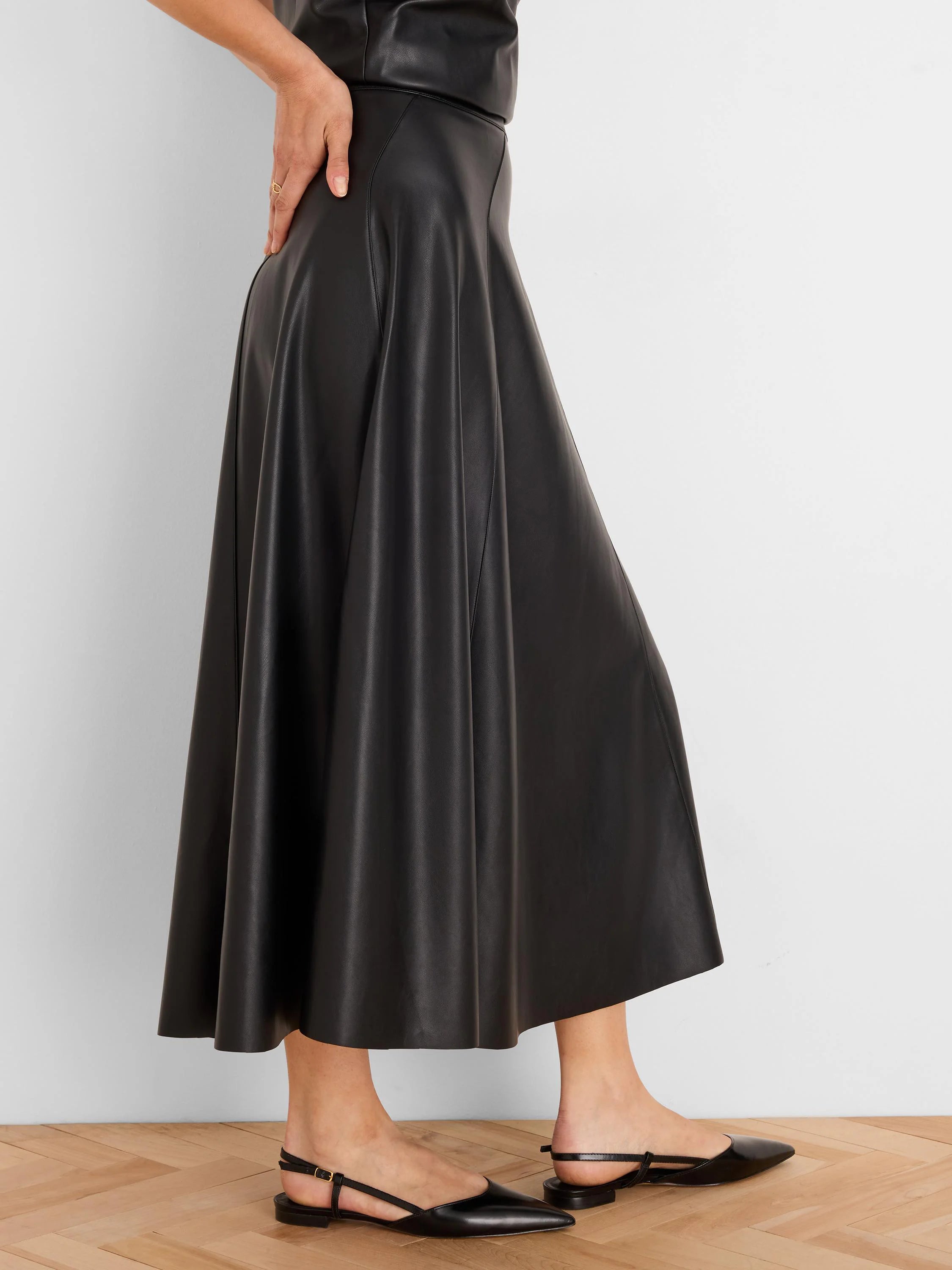 Black vegan leather seamed midi skirt with a flared silhouette.