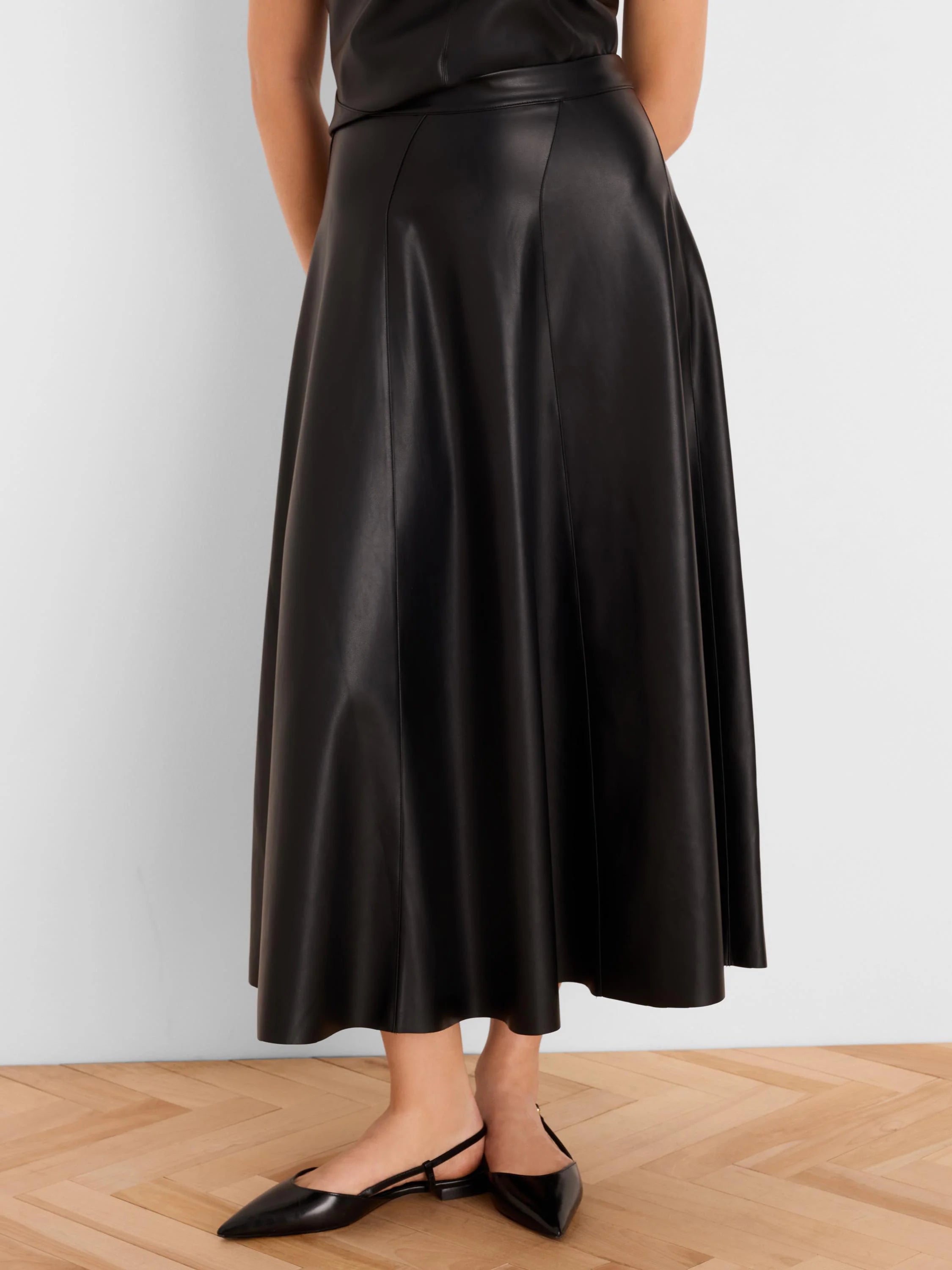 Black vegan leather seamed midi skirt, A-line and flared.