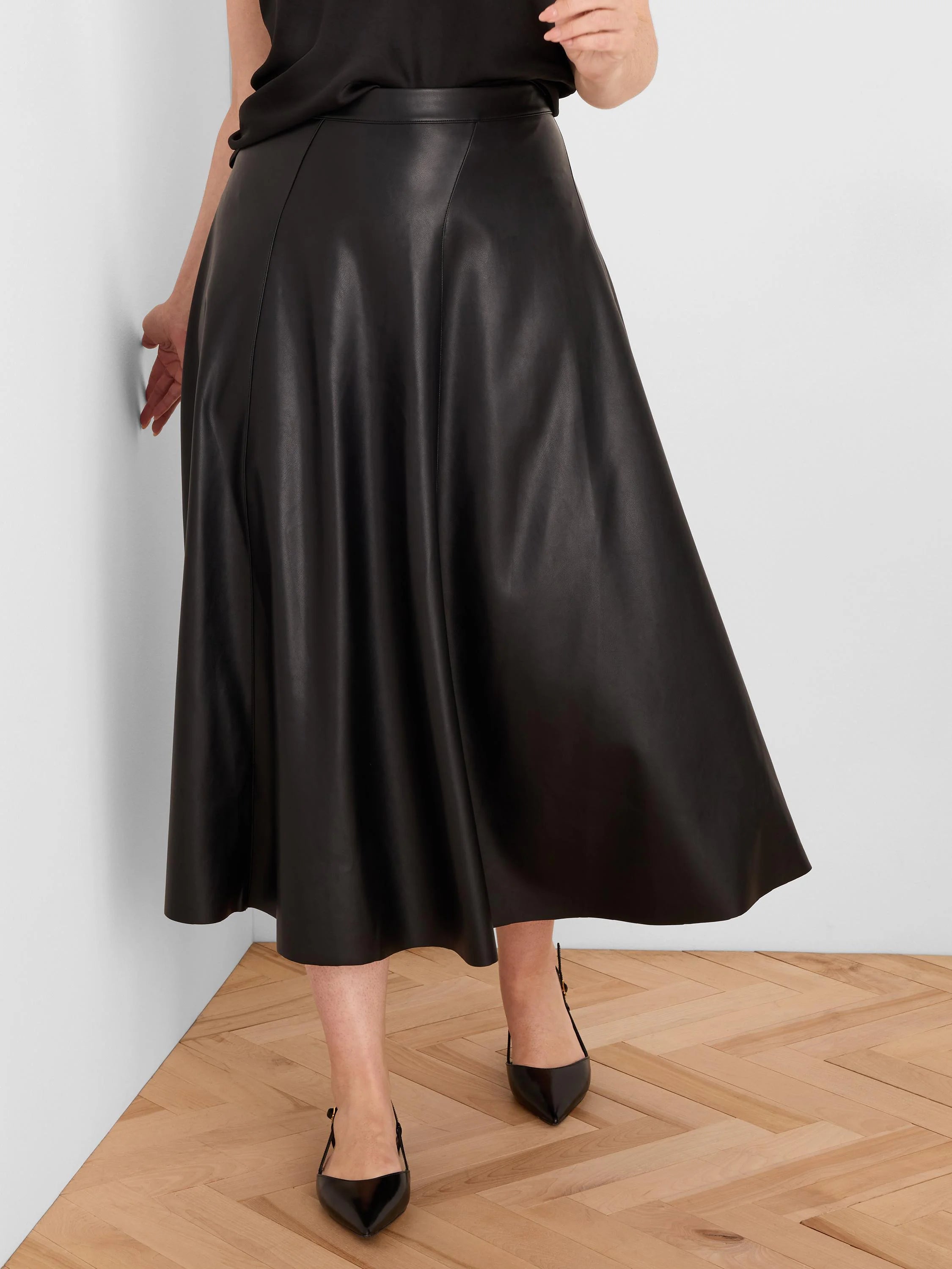 Black, seamed vegan leather skirt, mid-calf length with a flared silhouette.