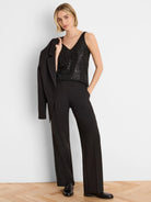Black wide-leg tuxedo pants with a vertical sequin stripe down the outer seam, shown on a standing model.