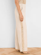 Beige wide-leg tuxedo pants with a vertical gold sequin stripe down the outer seam.