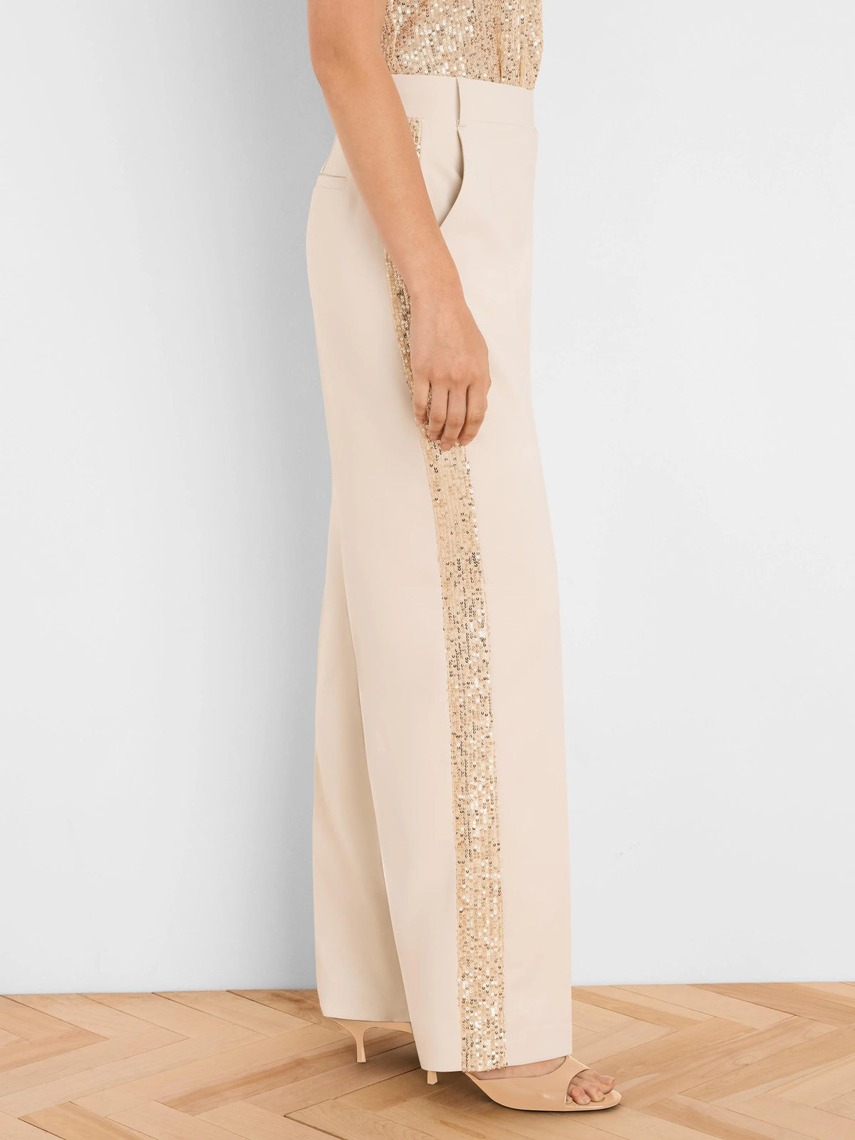 Beige wide-leg tuxedo pants with a vertical gold sequin stripe down the outer seam.