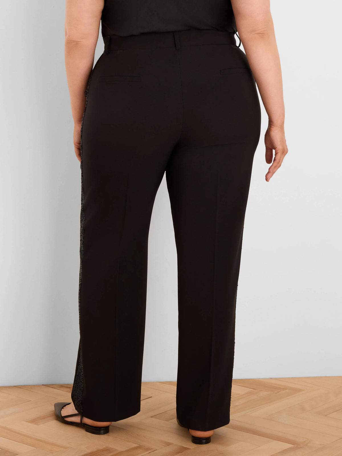 Black tuxedo pants, seen from behind, with dark sequin stripes along the outer seams of each leg.