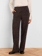 Dark brown wide-leg pants with a tan flecked print. A hand is in the front pocket.