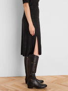 Black sequin knit midi skirt with a high side slit. Model wears tall black boots.