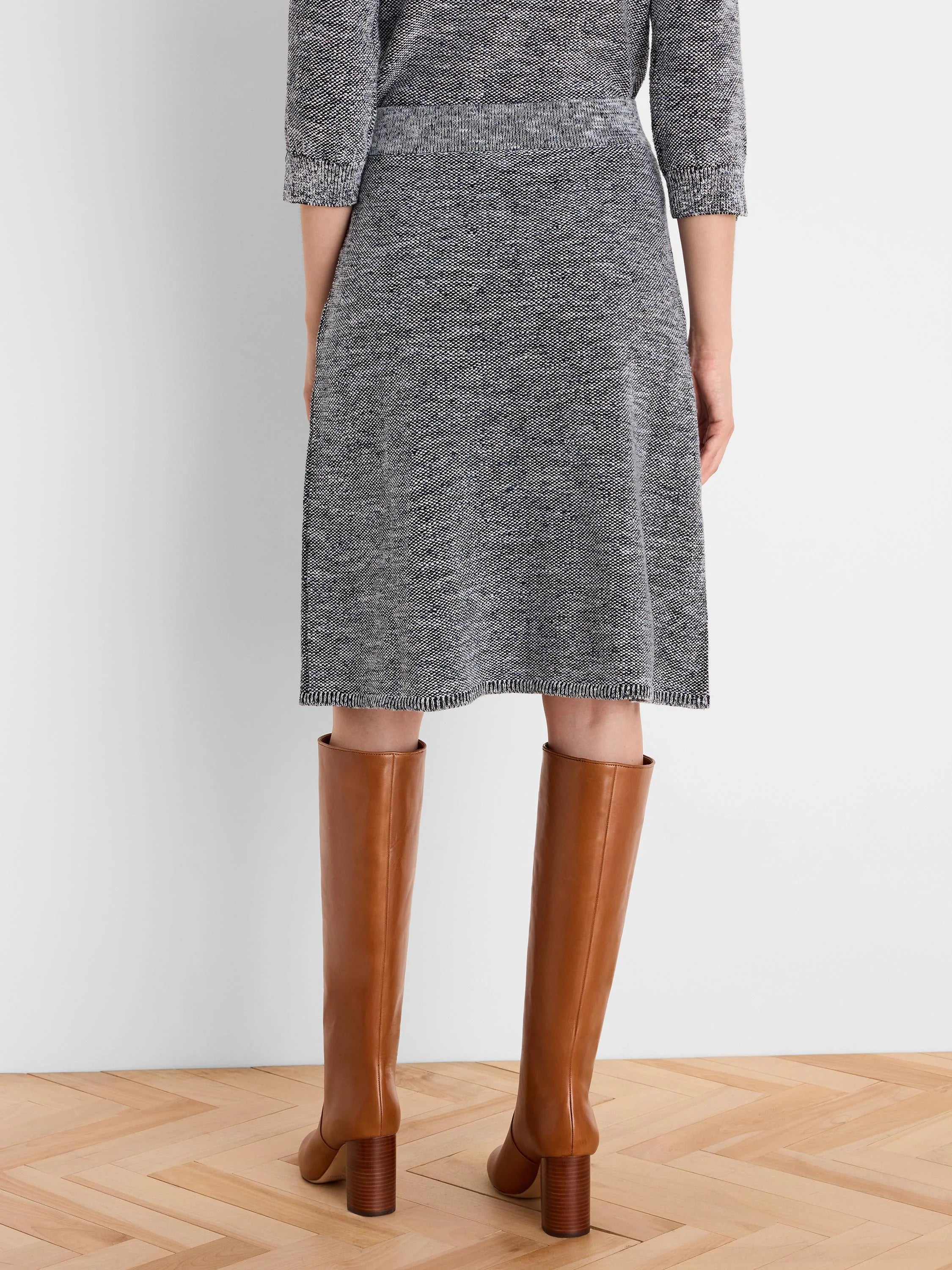 Dark grey tweed stitch knit A-line skirt with white & blue flecks. Ribbed waistband & hem. Knee-length.