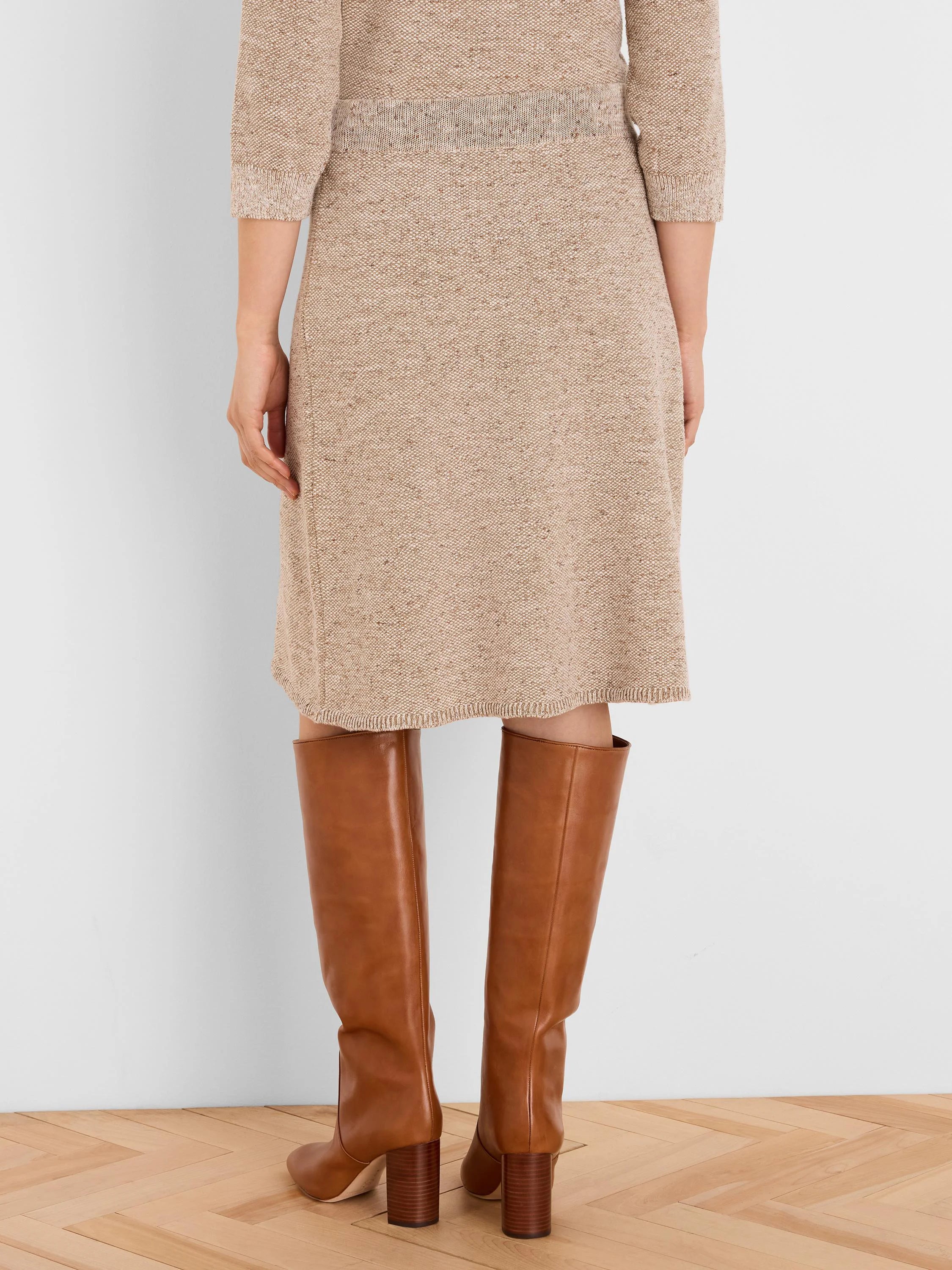 Speckled beige knit skirt, knee-length, with ribbed waistband and hem.