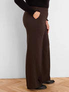 Dark brown, sleek wide-leg pants with side pockets, modeled from the side.