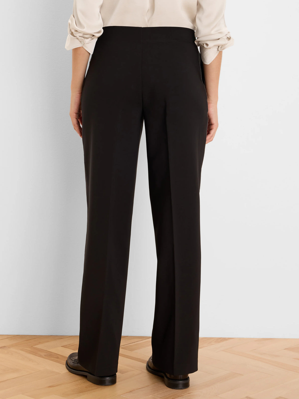 Back view of black wide-leg pants with accent stitching along the back of the legs and waistband.