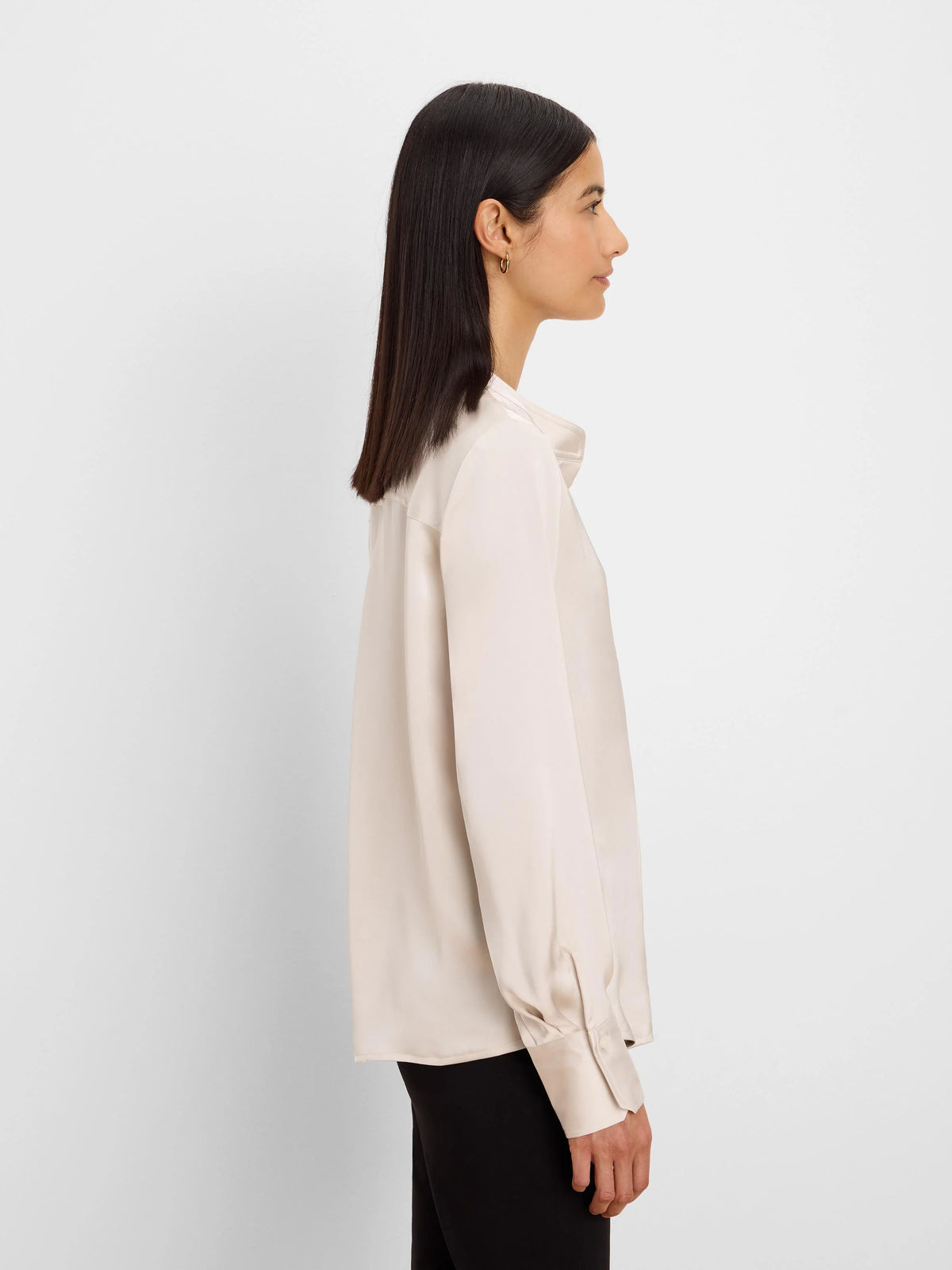 Light beige glossy shirt with a collar, long sleeves, and wide cuffs, worn by a model in profile.