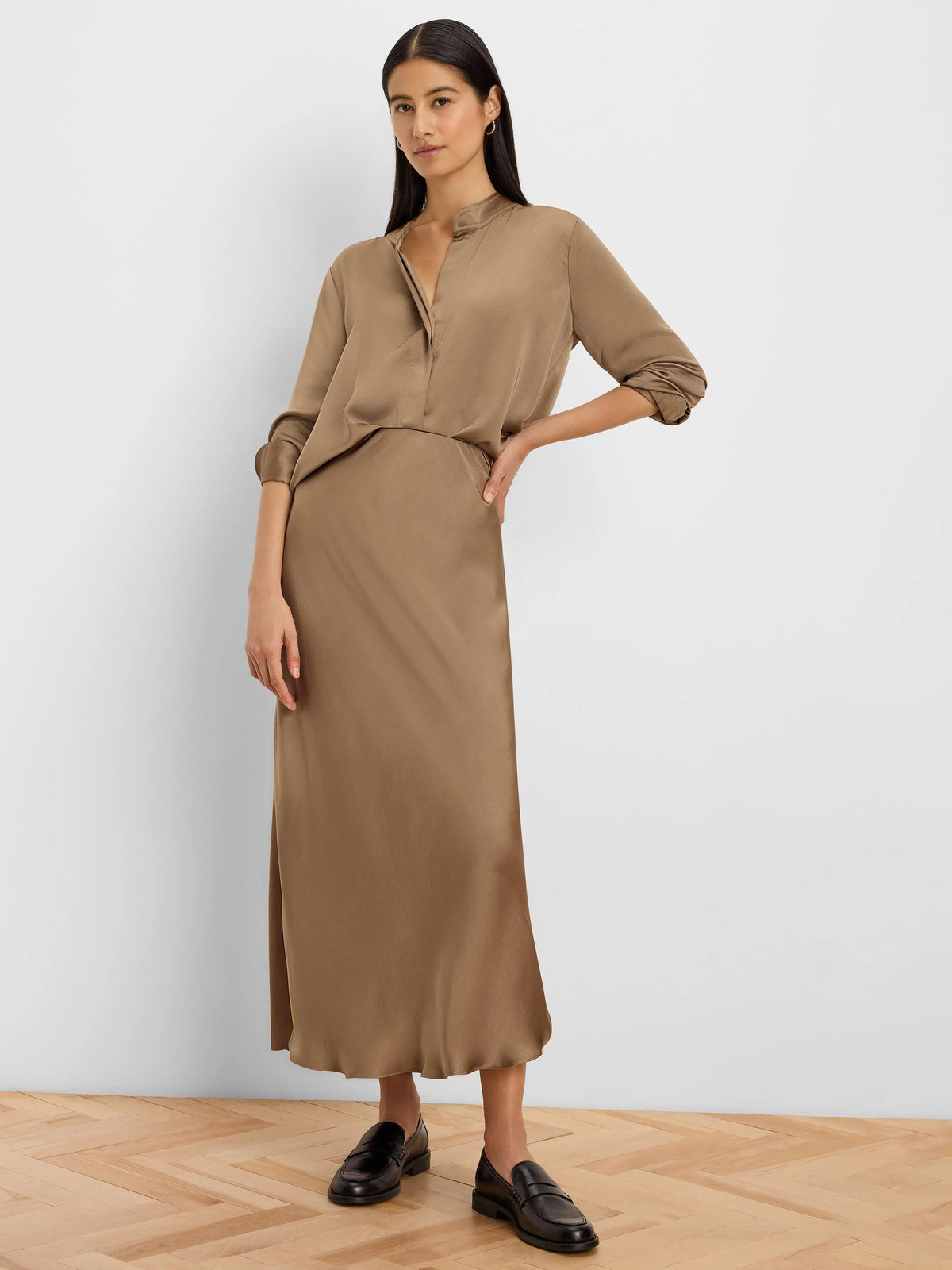Glossy taupe long-sleeve shirt with a band collar and V-neck. Sleeves are rolled up to the elbows.