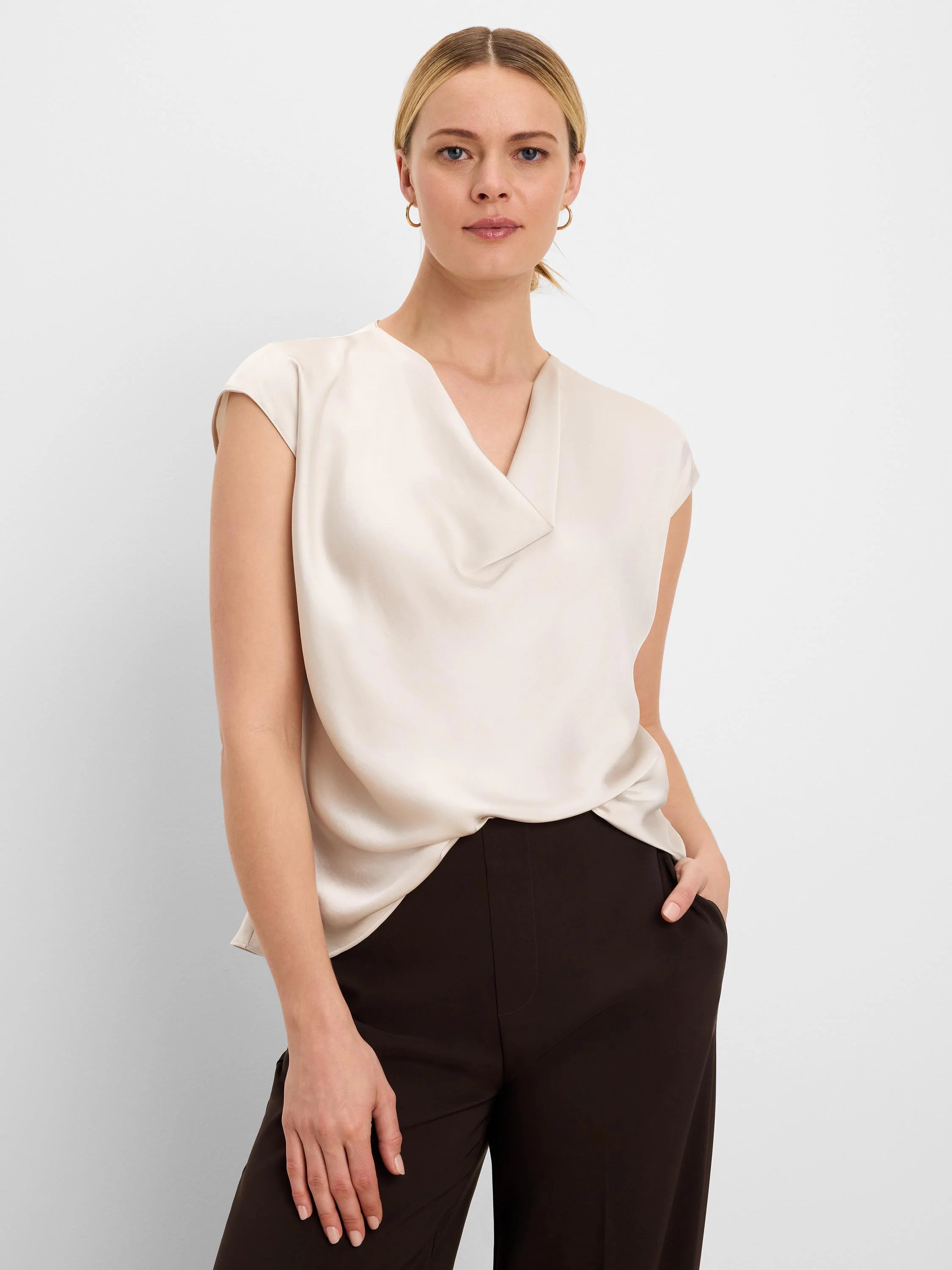 Cream, glossy tee with a draped V-neck and cap sleeves.