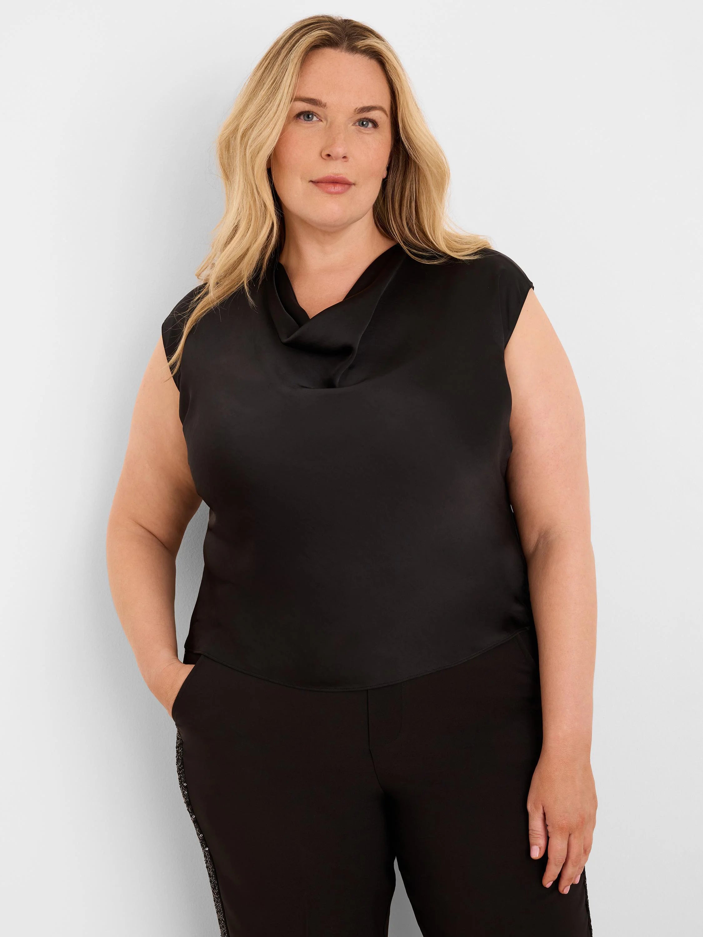 Black sleeveless tee with a draped neckline and glossy finish, modeled by a woman.
